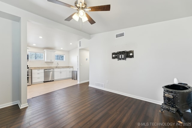 unfurnished living room with visible vents, a sink, a ceiling fan, and wood finished floors