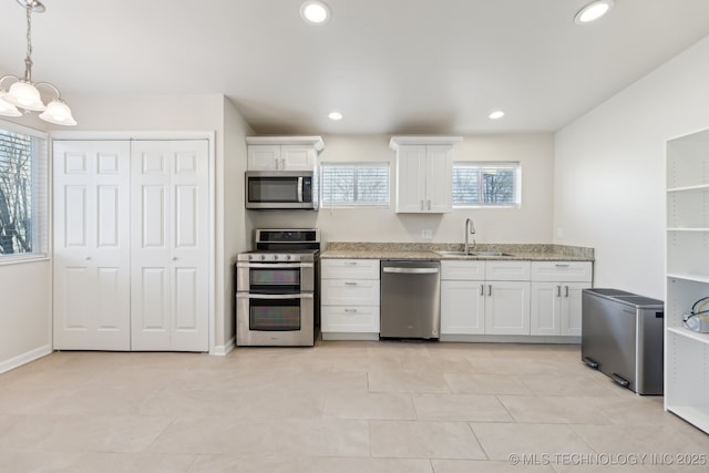 kitchen featuring recessed lighting, appliances with stainless steel finishes, a notable chandelier, white cabinetry, and a sink