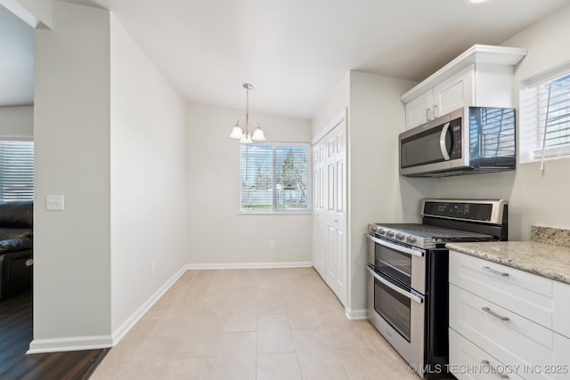 kitchen with light stone countertops, baseboards, stainless steel appliances, white cabinetry, and a chandelier