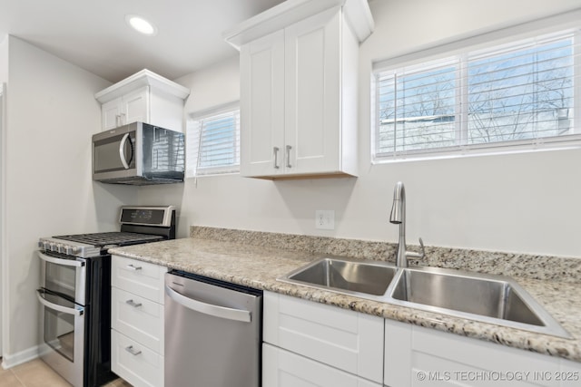 kitchen with light stone counters, recessed lighting, white cabinets, stainless steel appliances, and a sink