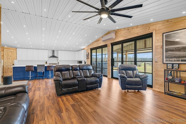 living room with a wealth of natural light, an AC wall unit, wood finished floors, wooden walls, and lofted ceiling