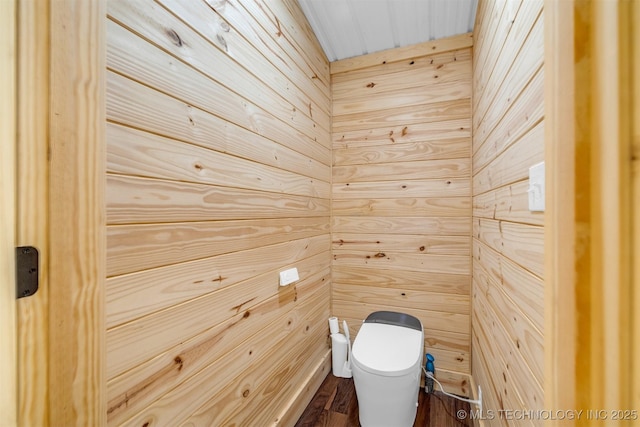 bathroom with wood walls and toilet