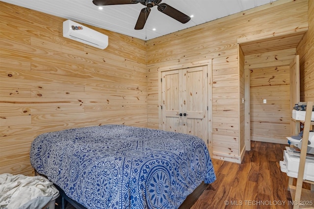 bedroom featuring a wall unit AC, wooden walls, a ceiling fan, wood finished floors, and a closet