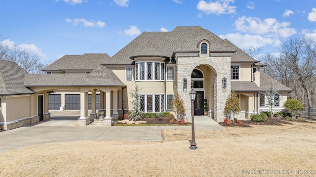 french country style house featuring stucco siding, stone siding, roof with shingles, and fence