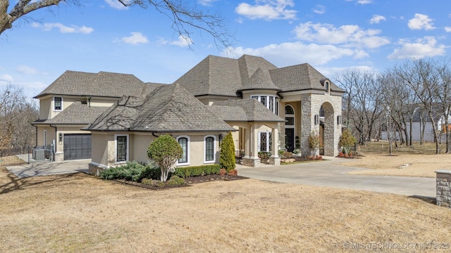 french provincial home with stone siding, stucco siding, driveway, and fence