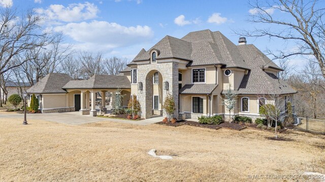 french country home featuring fence, driveway, stucco siding, a chimney, and stone siding