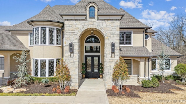 french country home featuring stucco siding, french doors, and a shingled roof