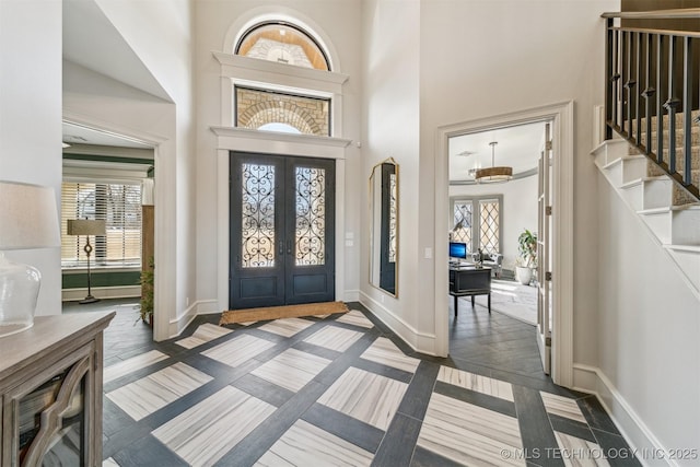 entryway featuring stairway, french doors, baseboards, and a towering ceiling