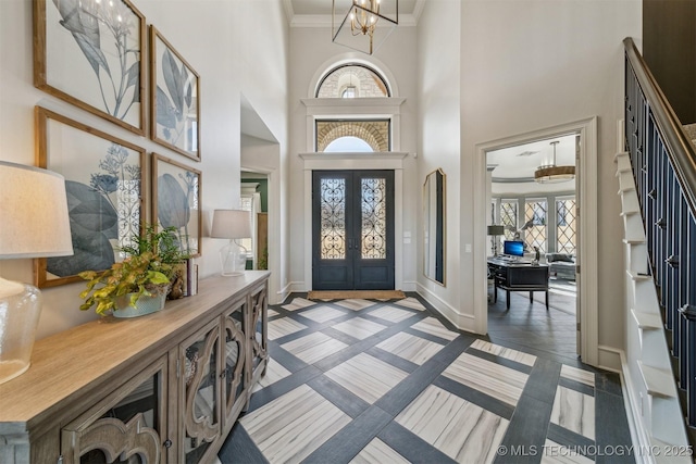 entrance foyer featuring french doors, baseboards, plenty of natural light, and ornamental molding