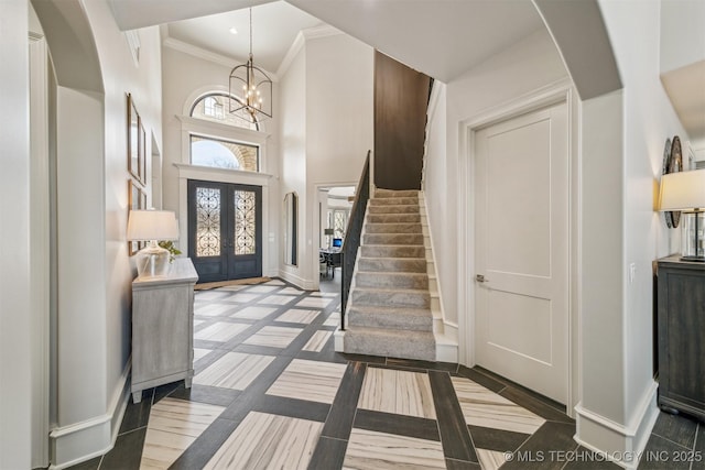 foyer entrance with baseboards, arched walkways, stairs, french doors, and a notable chandelier