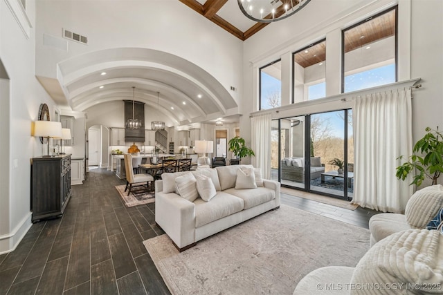 living area with dark wood-style floors, baseboards, visible vents, recessed lighting, and arched walkways