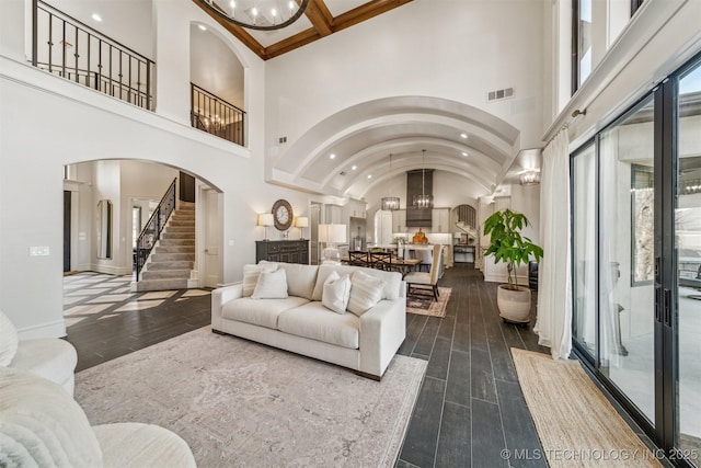 living room with arched walkways, visible vents, a healthy amount of sunlight, and dark wood finished floors