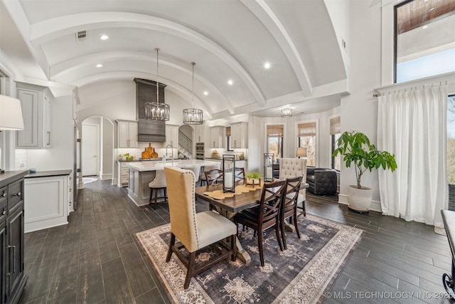 dining space featuring baseboards, dark wood finished floors, lofted ceiling, recessed lighting, and a chandelier