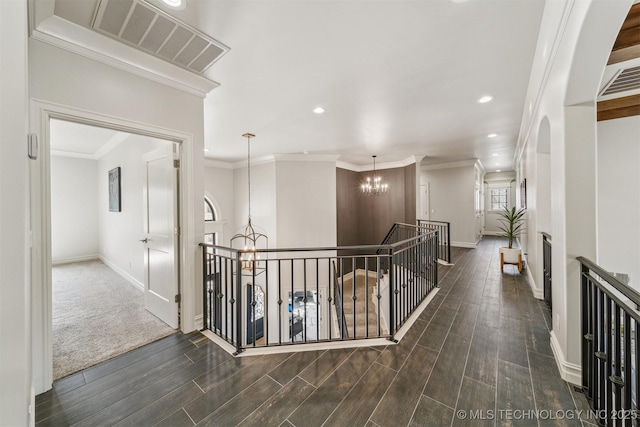 hallway featuring an inviting chandelier, crown molding, visible vents, and wood finish floors