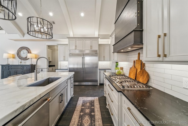 kitchen with beam ceiling, appliances with stainless steel finishes, tasteful backsplash, and a sink