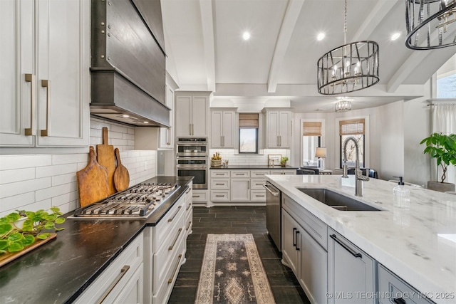 kitchen with a sink, stainless steel appliances, beam ceiling, and a notable chandelier