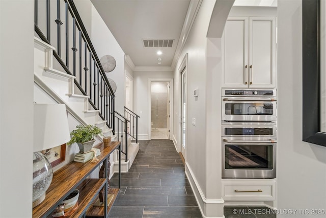 hall with stairway, baseboards, visible vents, wood finish floors, and ornamental molding