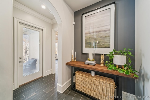 doorway featuring wood finish floors, baseboards, arched walkways, and recessed lighting