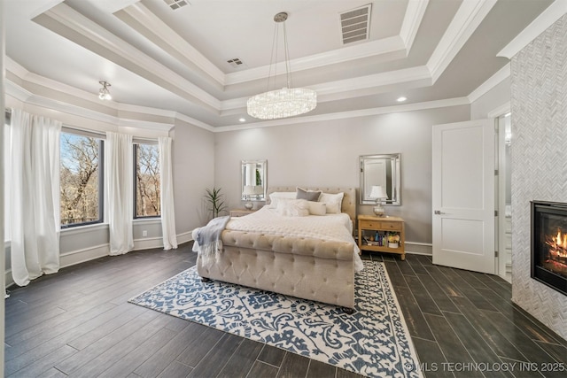 bedroom featuring visible vents, a fireplace, a raised ceiling, and wood tiled floor