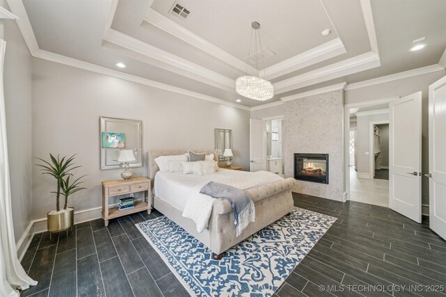 bedroom featuring a multi sided fireplace, visible vents, a raised ceiling, and wood tiled floor