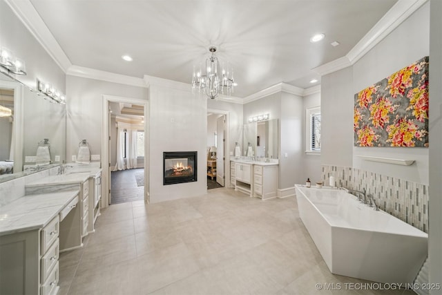 bathroom featuring crown molding, a freestanding bath, recessed lighting, a tile fireplace, and vanity