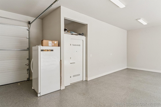 garage with baseboards and freestanding refrigerator