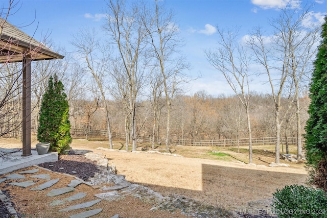 view of yard featuring a view of trees and fence