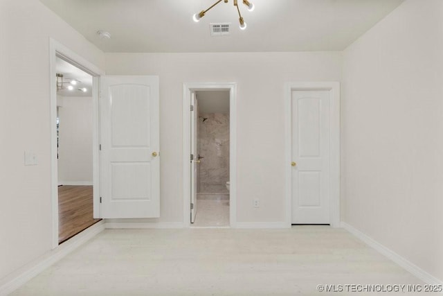 unfurnished bedroom featuring wood finished floors, visible vents, ensuite bathroom, and baseboards