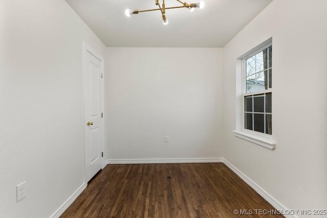 empty room with baseboards, dark wood-type flooring, and an inviting chandelier