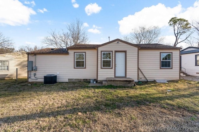 rear view of house featuring a yard, central AC unit, and fence