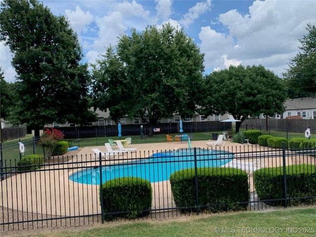 community pool with a patio area and fence