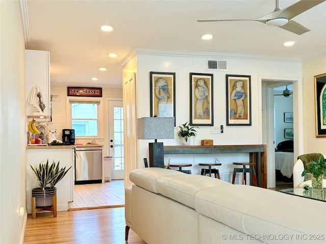 living room featuring visible vents, crown molding, recessed lighting, light wood-style floors, and a ceiling fan