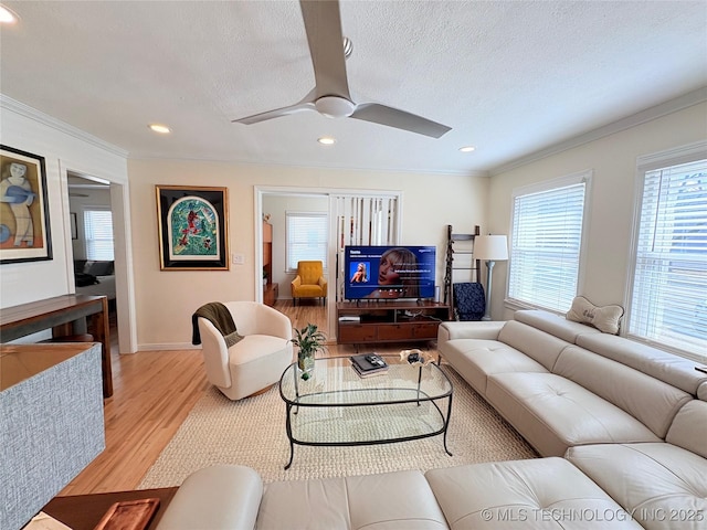 living room with recessed lighting, light wood-type flooring, a textured ceiling, and ornamental molding