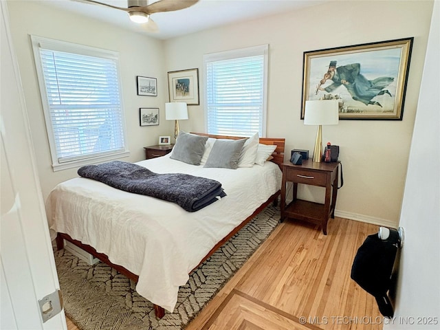 bedroom featuring multiple windows, baseboards, light wood-type flooring, and ceiling fan