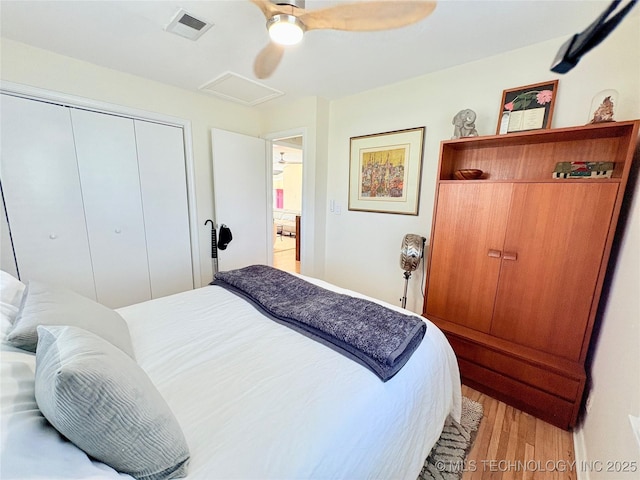 bedroom featuring visible vents, a closet, light wood finished floors, attic access, and ceiling fan