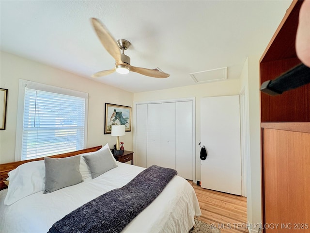 bedroom with a closet, light wood-style floors, attic access, and a ceiling fan