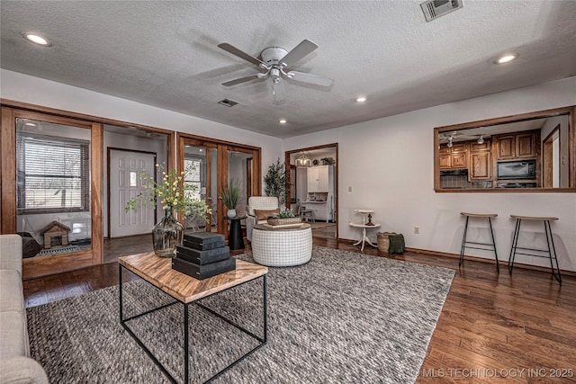 living room featuring recessed lighting, wood finished floors, visible vents, and a textured ceiling