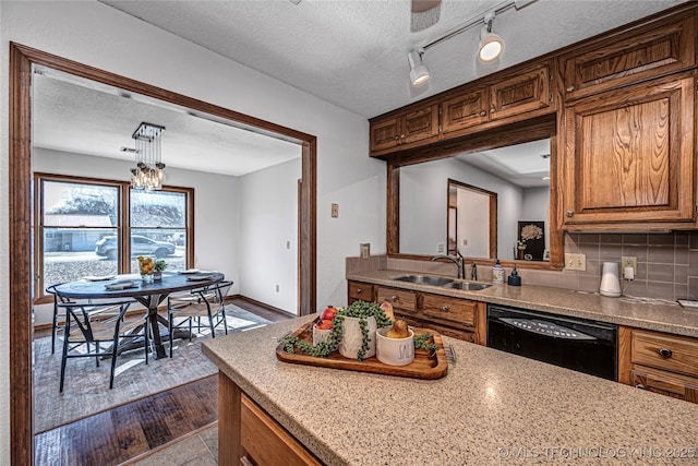 kitchen featuring a sink, tasteful backsplash, dishwasher, and a textured ceiling