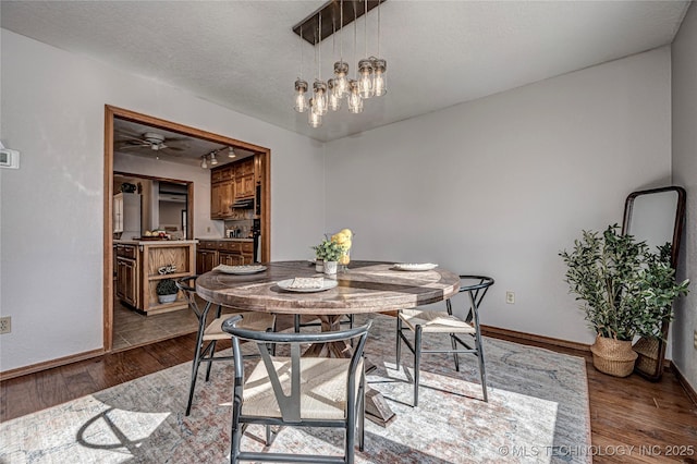 dining space featuring baseboards, a textured ceiling, an inviting chandelier, and dark wood finished floors