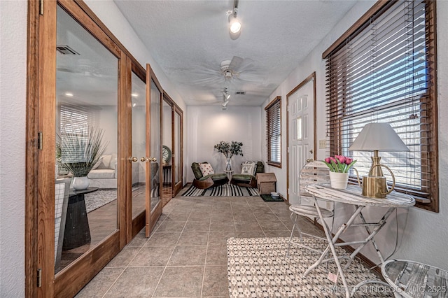 sunroom featuring french doors, a ceiling fan, visible vents, and track lighting