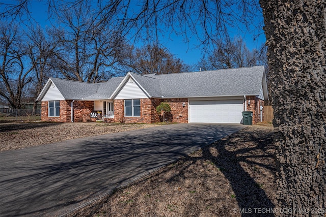 single story home with a garage, driveway, and a shingled roof