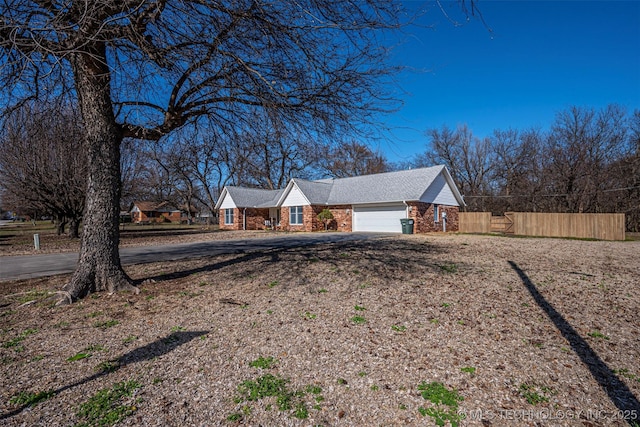 exterior space with fence, a garage, and dirt driveway