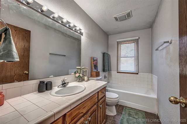 bathroom featuring visible vents, toilet, a textured ceiling, a bath, and a textured wall