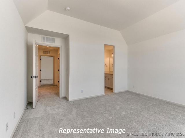 unfurnished bedroom featuring visible vents, light colored carpet, baseboards, and lofted ceiling