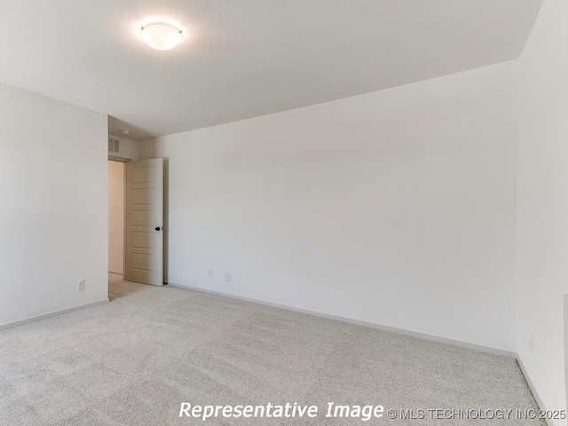 empty room featuring light carpet, visible vents, and baseboards