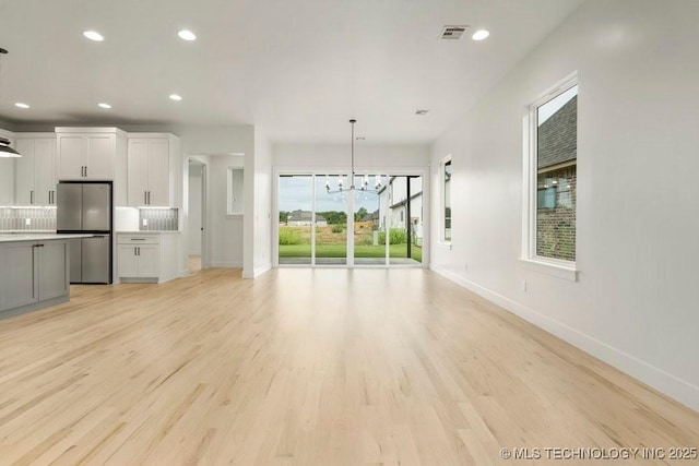 unfurnished living room with recessed lighting, visible vents, baseboards, and light wood finished floors