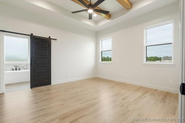 unfurnished room featuring baseboards, a ceiling fan, a barn door, and wood finished floors