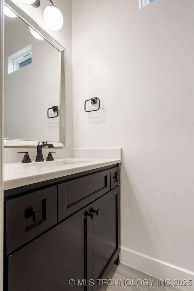 bathroom featuring vanity, wood finished floors, and baseboards