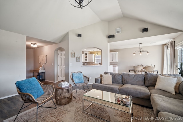 living area with visible vents, baseboards, wood finished floors, arched walkways, and high vaulted ceiling