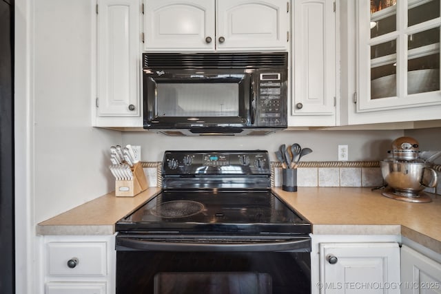 kitchen with glass insert cabinets, white cabinetry, black appliances, and light countertops